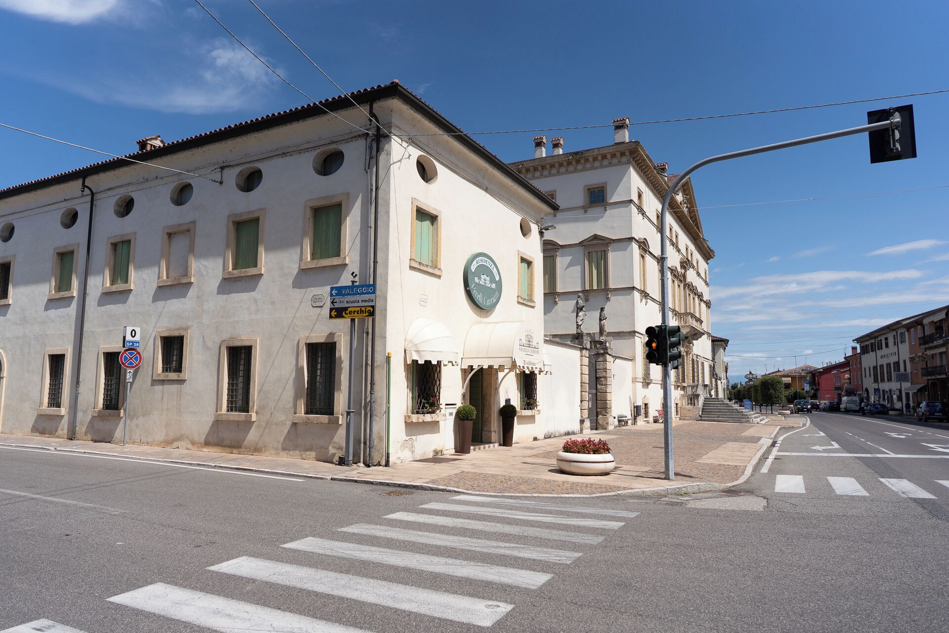 A building with a classical architectural style, featuring a central entrance with a canopy, and a sign indicating a school nearby.