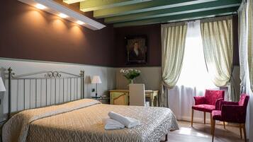 A hotel room with a bed, a desk, a chair, and a window with curtains.