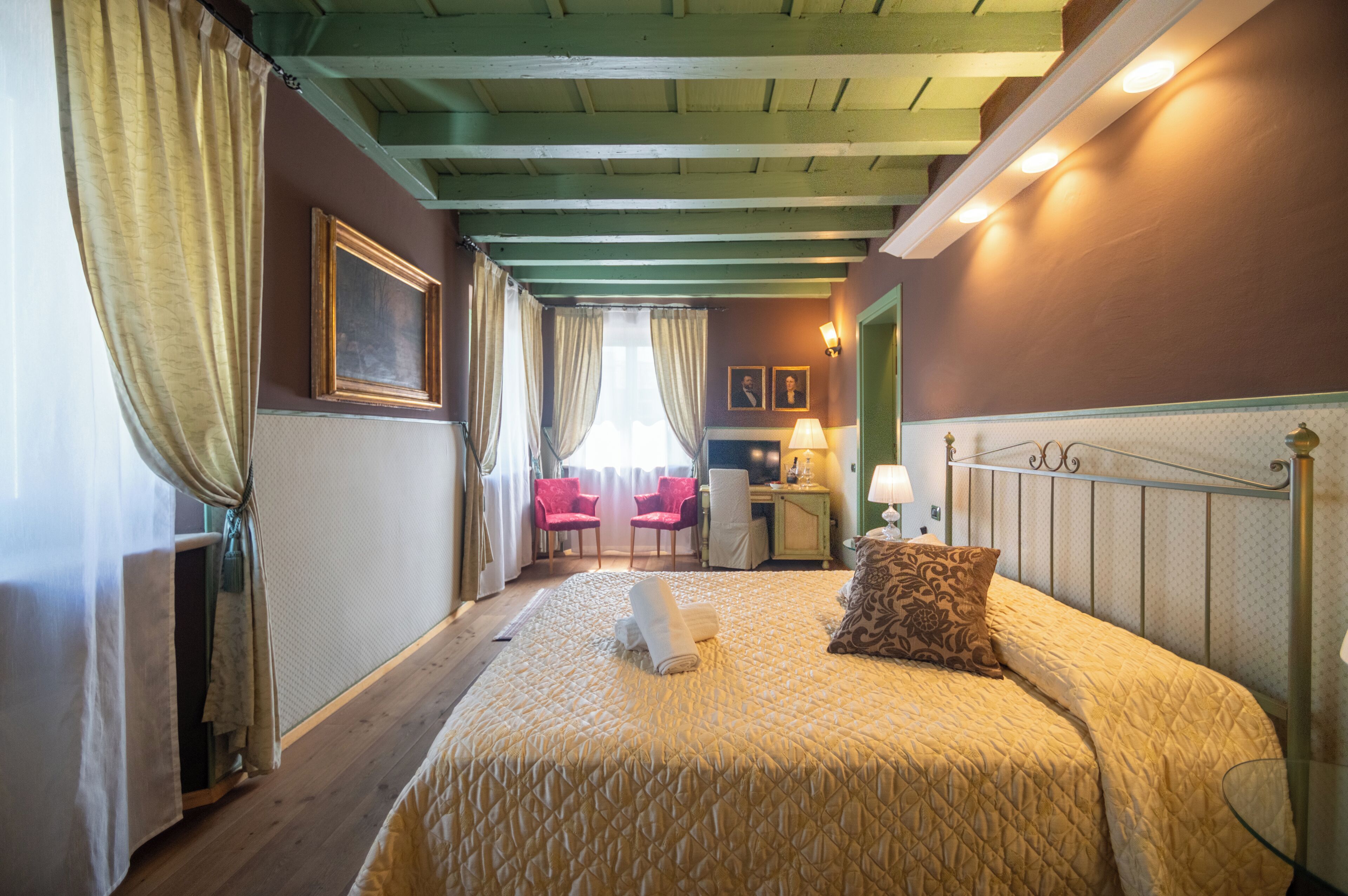 A hotel room with a bed, a desk, a chair, and a lamp.