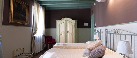 A bedroom with a bed, a wardrobe, a chair, and a painting on the wall.