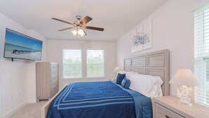 A bedroom with a bed, a nightstand, a dresser, a ceiling fan, and a TV on the wall. - Beach Getaway Community Amenities! (Panama City Beach)