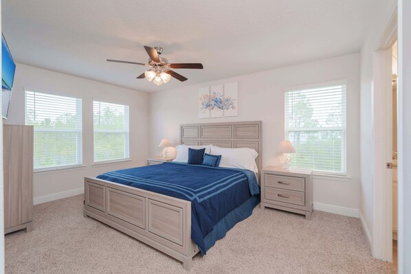 A bedroom with a bed, nightstands, a ceiling fan, and two windows with blinds. - Beach Getaway Community Amenities! (Panama City Beach)