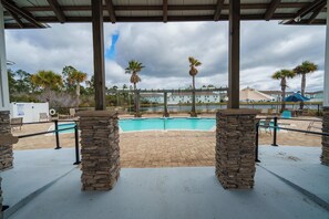 A pool area with stone pillars, a covered seating area, and palm trees.