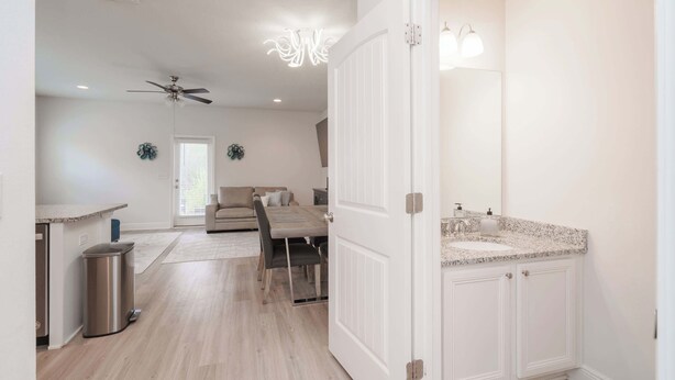 A modern kitchen with white cabinetry, a granite countertop, and a ceiling fan. - Beach Getaway Community Amenities! (Panama City Beach)