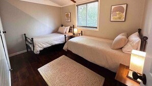 Een slaapkamer met twee bedden, een raam en een deur.