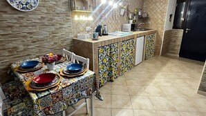 A kitchen with a dining table set for four, a microwave, a sink, and a refrigerator. - In the heart of Naples. Pets allowed. Stroller and crib available free of charge. (Napoli)