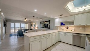 A spacious kitchen with white cabinetry, a large island, and a ceiling fan. - Pelican Watch #205 Stunning Beachfront Condo (Fort Myers Beach)
