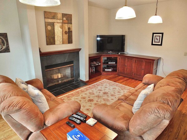 Una sala de estar con chimenea, televisor y un juego de sofá.