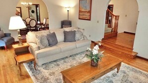 Een woonkamer met een bank, salontafel en lamp. Een trap leidt naar een hoger gelegen verdieping.