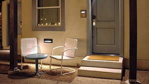 A hotel entrance with a door, two chairs, and a small table. - The Dixie Motel Brenham (Brenham)