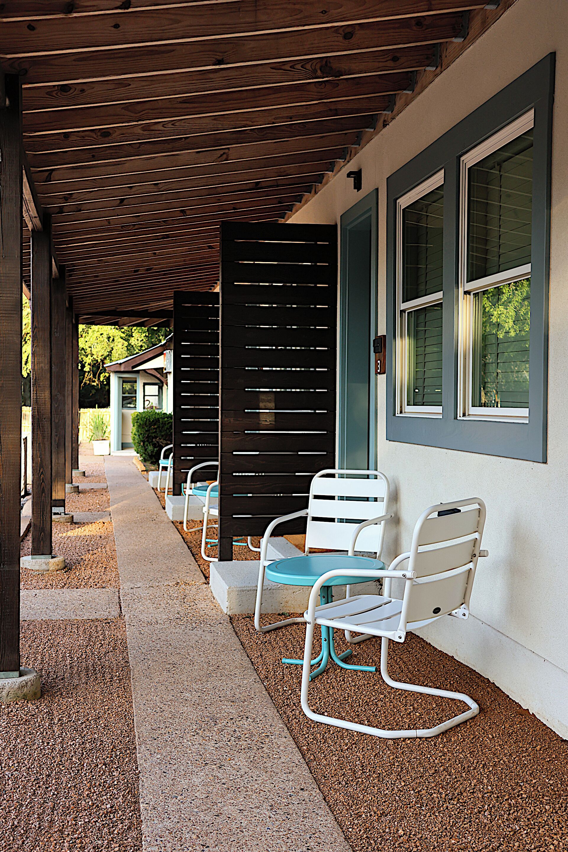 An outdoor seating area with metal chairs and a wooden pergola.