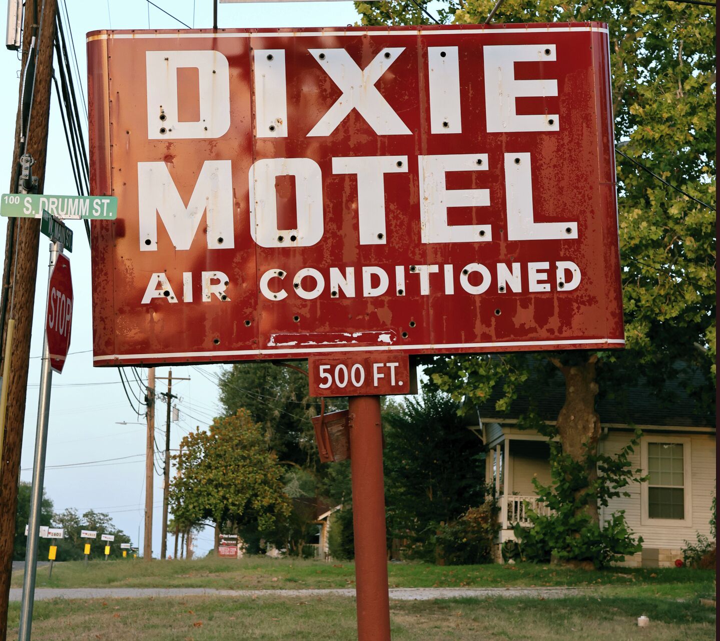 En röd skylt för ett motell, med vita bokstäver som visar texten ”Dixie Motel, luftkonditionering” och ”500 fot”.