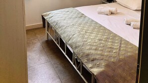 Een slaapkamer met een bed, nachtkastje, raam met gordijnen en een hanglamp.