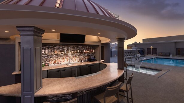 A bar area with a poolside view, featuring a curved bar, seating, and a pool. - Dream Las Vegas Retreat Steps from the Strip! (Las Vegas)