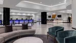 A modern lobby with a reception desk, a curved sofa, and teal armchairs. - Dream Las Vegas Retreat Steps from the Strip! (Las Vegas)
