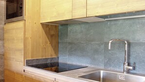 Una cocina con armarios de madera, un lavamanos de acero inoxidable y una estufa negra.