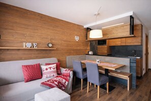 En moderne stue med sofa, spisebord og et køkkenhjørne.