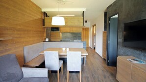 Una cocina moderna con armarios de madera, un comedor con mesa y sillas, y un televisor de pantalla plana montado en la pared.