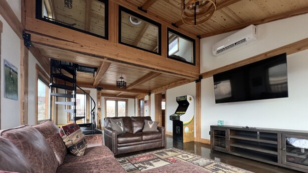 Un salon spacieux avec un grand canapé d’angle, un téléviseur à écran plat et un ventilateur de plafond.