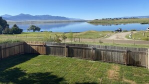 Un jardin clôturé donnant sur un lac et des montagnes.