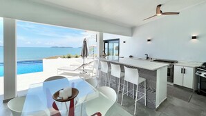 Une cuisine moderne dotée d’un grand îlot central, d’un coin bar et offrant une vue sur la mer.