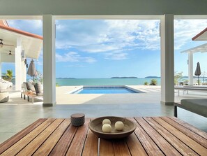 A wooden table with a bowl and a decorative item, a pool, and a view of the sea and islands. - Ocean Front Villa in Boca Chica! (Boca Chica)