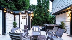 An outdoor patio with Adirondack chairs, a table, and string lights. - Gatsby Theme Near Downtown w Game Room, EV Charger (Lake Geneva)