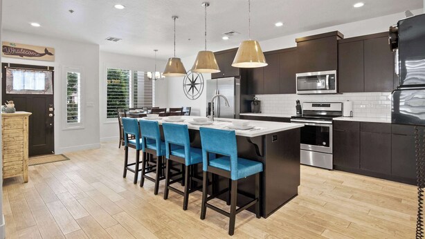 A modern kitchen with dark cabinets, a central island, blue bar stools, and pendant lighting. - By the Sea Ocean Vibes in the Mountains! (Washington)