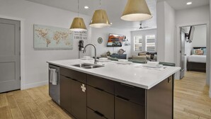 A modern kitchen with a large island, pendant lights, and a world map on the wall. - By the Sea Ocean Vibes in the Mountains! (Washington)