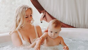 Una mujer y un bebé en un jacuzzi con vistas a árboles.