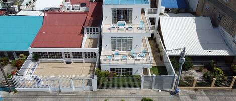 A multi-story building with a rooftop pool, a fenced parking area, and a street view with a parked vehicle.