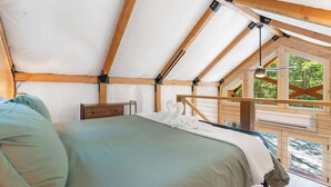 A tented accommodation with a bed, wooden beams, and a view of greenery. - Cedar Creek - Glamping in the Ozarks! (Walnut Shade)
