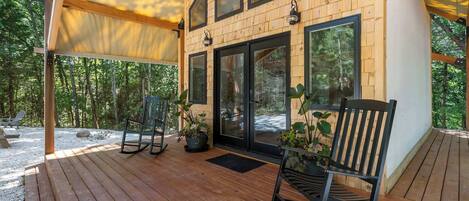 A wooden deck with a covered seating area, a large sliding glass door, and potted plants.