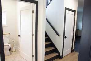 Ein Badezimmer mit Toilette und Toilettenpapier, eine Treppe mit Handlauf und eine Tür, die in einen anderen Raum führt.