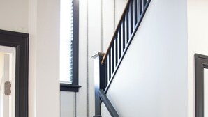 Eine Treppe mit Holzstufen und schwarzen Geländern, die zu einer Empore mit einem Fenster führt.