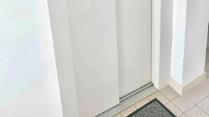 A closed white door with a modern handle, a small mat at the base, and a light switch on the wall.