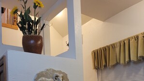Een trap met een stenen sculptuur, een vaas met zonnebloemen en een raam met luiken.