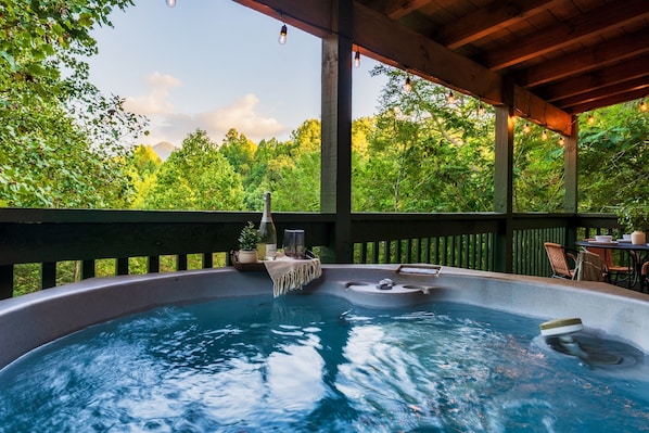 Un bain à remous sous une pergola en bois, avec vue sur une végétation luxuriante.