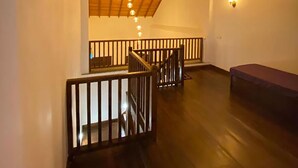 A spacious loft with a high ceiling, wooden beams, a staircase, and a hanging light fixture. - The Dutch Boutique (Galle)