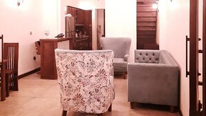 A spacious living area with a high ceiling, a dining table, and two chairs. There is a staircase leading to an upper level. - The Dutch Boutique (Galle)