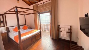 A four-poster bed with orange pillows, a wooden ceiling, a balcony with curtains, and a towel rack. - The Dutch Boutique (Galle)