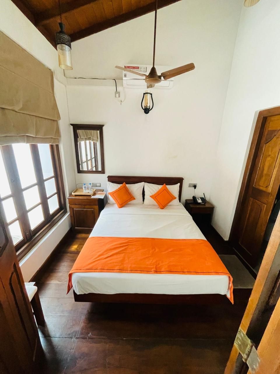 A bedroom with a bed, a nightstand, a lamp, a ceiling fan, and a window.