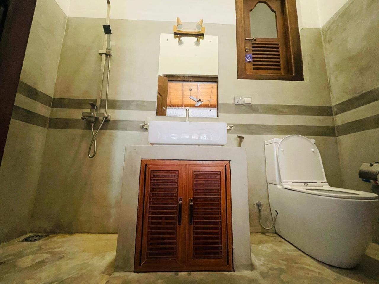 A bathroom with a shower, toilet, and a mirror above the sink.