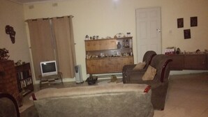 A living room with a sofa, a television, a cabinet with decorative items, and a door. - Christy Mwila Chisenga (Kitwe)