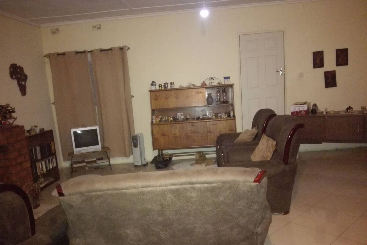 A living room with a sofa, a television, a cabinet with decorative items, and a door.