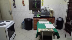 A compact kitchen with a stove, a table with a green tablecloth, and a microwave. - Christy Mwila Chisenga (Kitwe)