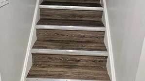 Un escalier avec des marches en bois et des moulures blanches menant à une porte dotée d’une fenêtre.