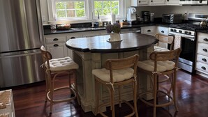 A kitchen with a central island, wooden chairs, a stainless steel refrigerator, and white cabinets. - Home in Historic old downtown Summerville... (Summerville)