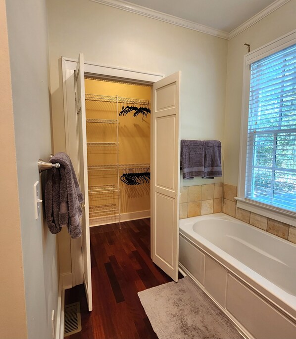Un baño con vestidor, bañera y ventana con persianas.