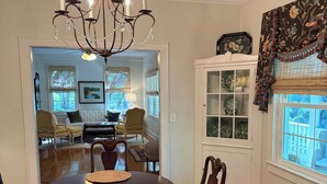 A dining room with a large round table, chairs, a chandelier, and a cabinet with glass doors. - Home in Historic old downtown Summerville... (Summerville)